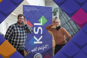 Ein Foto von Andreas Heither ein junger Mann mit Brille und einem karierten Hemd - und Wibke Roth - eine Frau mit Brille und einer goldfarbigen Strickjacke/beide halten jeweils eine Hand an ihr Ohr - ein Symbolbild, das es sich hier um KSL aufs Ohr - ein Hörbeitrag der KSL.NRW handelt/Links steht auf bunten Kacheln (Stilelemente der KSL.NRW) Fensterblick NRW - der Expert*innen-Blog