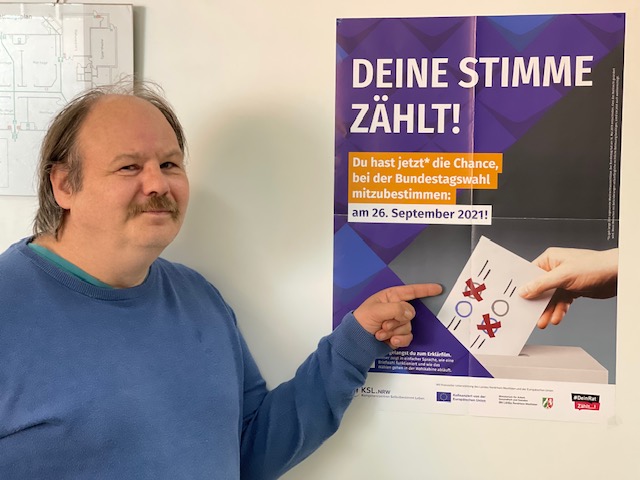 Man sieht Gerd Ziegler der auf ein Plakat der Kampagne "Deine Stimme Zählt" zeigt